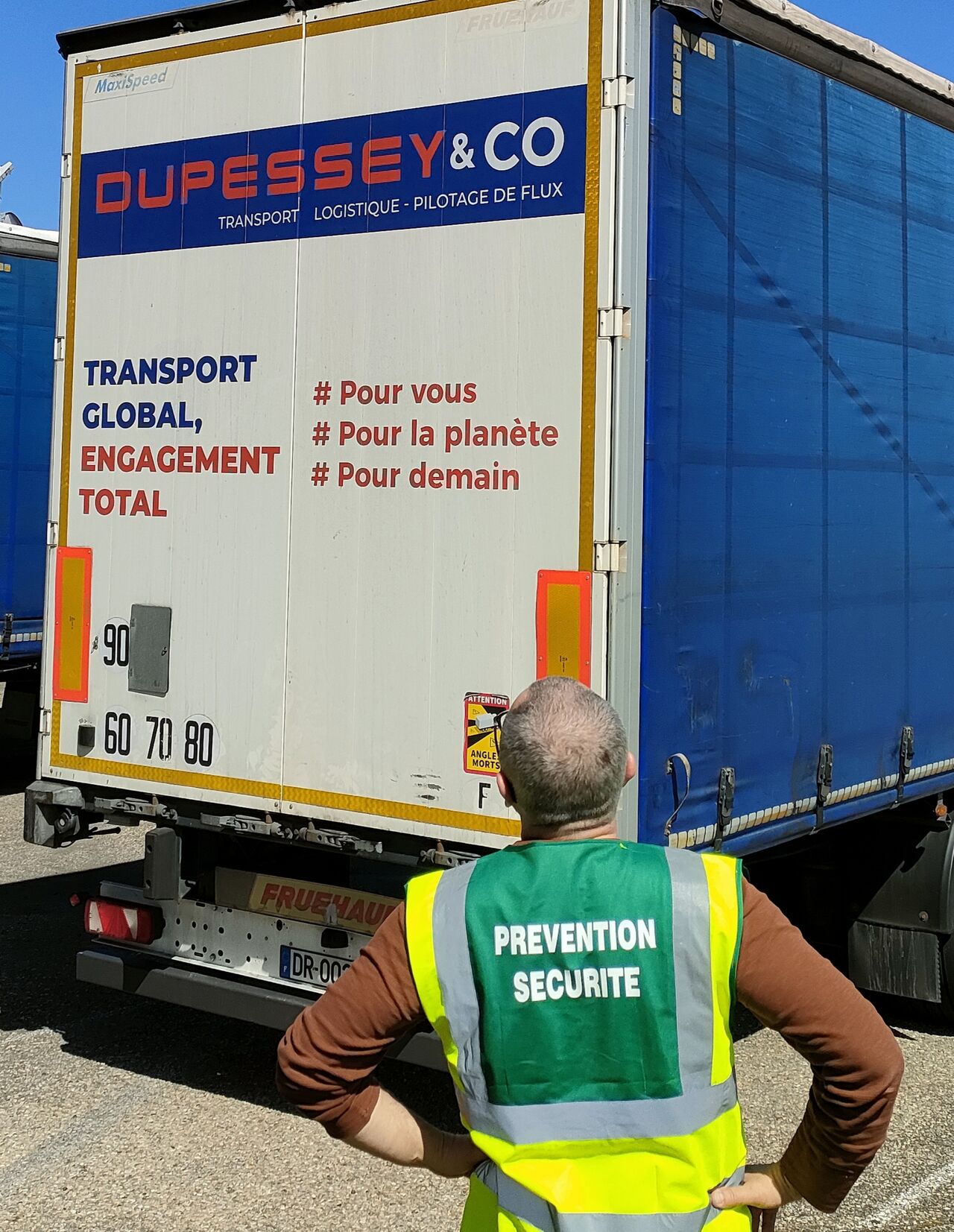 Notre responsable QHSE, sur notre parc roulant avec un gilet de sécurité